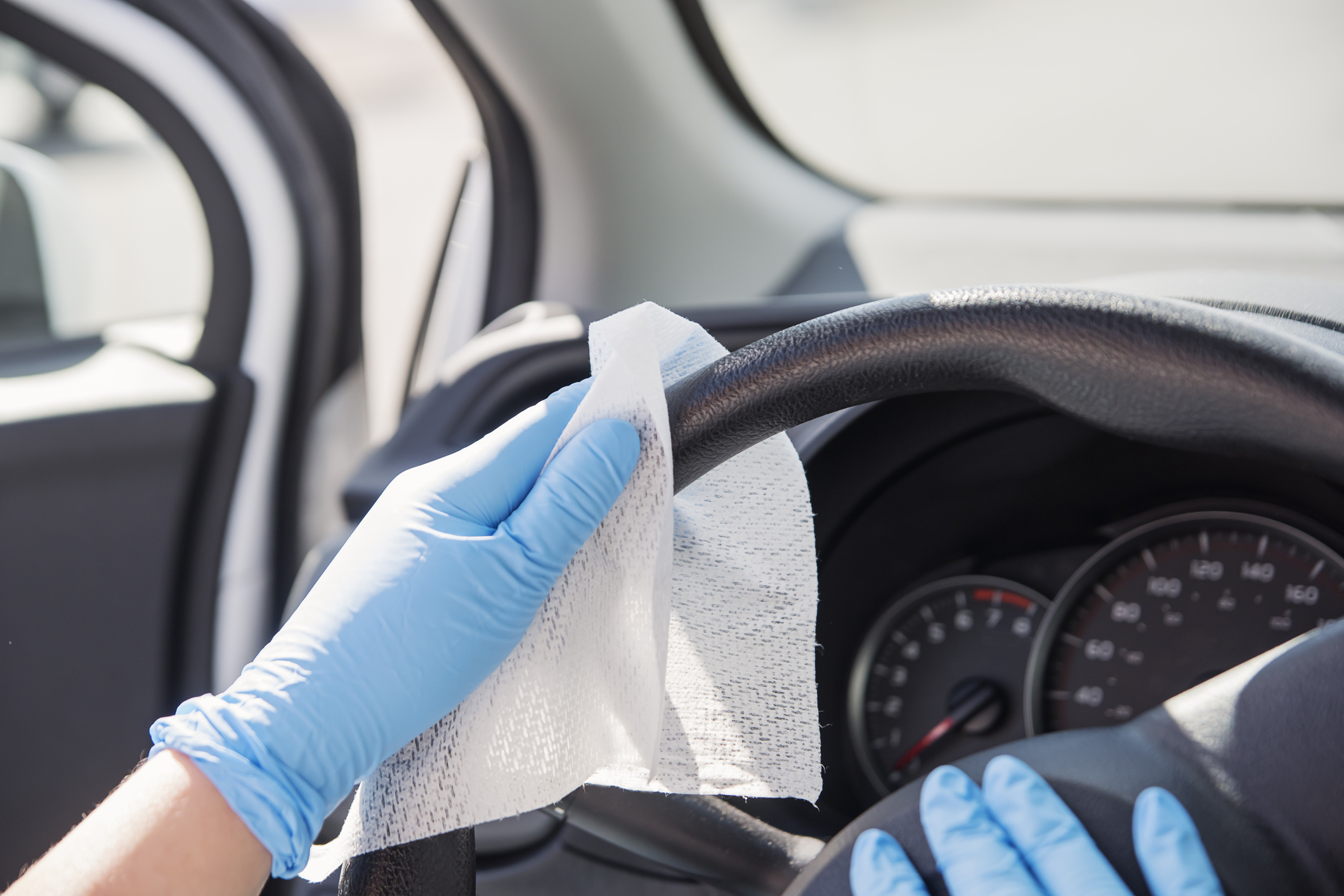 Hands with glove wiping car steering wheel