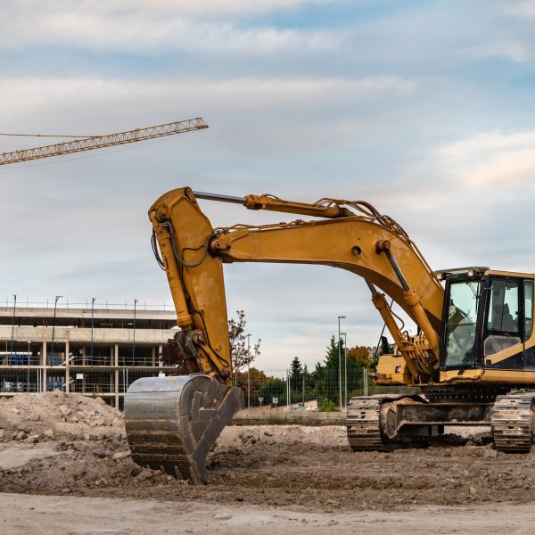 Excavator at a construction site with cranes
